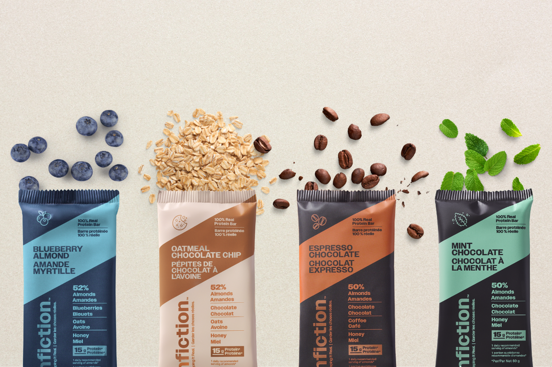 All four Nonfiction protein bars laid out on a plain background. Almond blueberry, oatmeal chocolate chip, coffee chocolate and mint chocolate. Each bar lays on top of real ingredients, blueberry, oatmeal, coffee and mint leaves